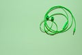 Green earphones bent in shape of human face on green paper background Royalty Free Stock Photo