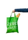 Green eco bag with a white text zero waste in the hand isolated on white background. Royalty Free Stock Photo