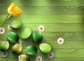 Green eggs and spring flowers on a green wooden background