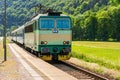 A green electric locomotive passing the Czech countryside