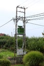 Green electric power transformer with metal utility box on high utility pole connected with multiple electrical wires