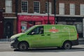 Green electric Royal Mail van on a street in London, UK