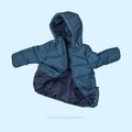 Green emerald flying children`s winter autumn jacket with hood isolated on blue background. Waterproof jacket for child, warm dow Royalty Free Stock Photo