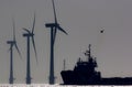 Green energy. Offshore wind farm turbines with ship at sea. Silhouette at dawn. Royalty Free Stock Photo