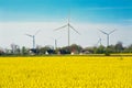 Ecological energy, wind farm over houses and rapeseed field. Beautiful landscape in Poland. Royalty Free Stock Photo