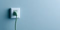 A green Ethernet cable plugged into a white electrical outlet on a blue wall Royalty Free Stock Photo