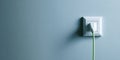 A green Ethernet cable plugged into a white electrical outlet on the side of an off-white wall Royalty Free Stock Photo