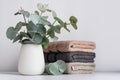 Green eucalyptus leaves in vase and bathroom towels on white table