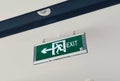 Green exit sign with white icon symnol hanging on the ceiling Royalty Free Stock Photo