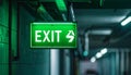 Green exit sign with white lettering and arrow pointing right in a dimly lit corridor Royalty Free Stock Photo