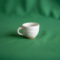 A green fabric background. The cup features a rounded handle and a Royalty Free Stock Photo