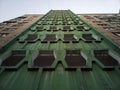 Green facade of a multi-storey residential building with windows in the shape of honeycombs, bottom-up view