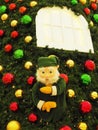 Green fairy troll hanging on a christmas tree with glossy balls under the decorative window