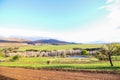 Green farm landscape with gravel road in foreground and mountains in the background Royalty Free Stock Photo