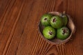 Green feijoa in a coconut shell hulf on a wooden background. Ripe tropical fruits, raw vegan food.Vitamin C. Copy space. Royalty Free Stock Photo