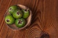 Green feijoa in a coconut shell hulf on a wooden background. Ripe tropical fruits, raw vegan food.Vitamin C. Copy space. Royalty Free Stock Photo