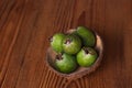 Green feijoa in a coconut shell hulf on a wooden background. Ripe tropical fruits, raw vegan food.Vitamin C. Copy space Royalty Free Stock Photo