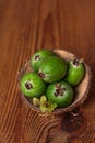 Green feijoa in a coconut shell hulf on a wooden background. Ripe tropical fruits, raw vegan food.Vitamin C. Copy space Royalty Free Stock Photo