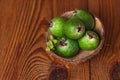 Green feijoa in a coconut shell hulf on a wooden background. Ripe tropical fruits, raw vegan food.Vitamin C. Copy space Royalty Free Stock Photo