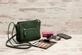 Green female bag, phone, eyeshadow palette, phone, sunglasses and lipstick on a wooden background. Royalty Free Stock Photo