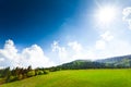 Green field with barn, mountains on background