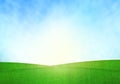 Green field, blue sky and lighting flare on grass.