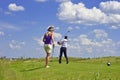 Green field and cloudy blue sky, golf players