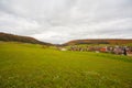 a green field with houses in the distance and a cloudy sky above it, with a few clouds in the sky Royalty Free Stock Photo