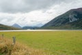 Green field and lake surrounded by mountains Royalty Free Stock Photo