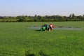 A green field landscape with crop sprayer spraying chemicals fertilizer, herbicides and pesticides. Agriculture ecology