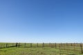 Green field surrounded by plain wooden fence