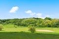 Green field and trees in a sunny summer day with blue bright sky and white clouds Royalty Free Stock Photo