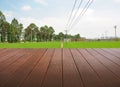 Synthesis of textured wooden planks floor and green field background.