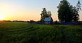 Green field and village house on sunset background.