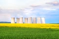 Green field, yellow rapeseed field, cooling towers of nuclear power plant in background Royalty Free Stock Photo