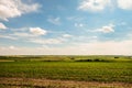 Green fields with ravines to the horizon under a blue cloudy sky Royalty Free Stock Photo