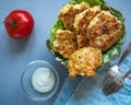 Green figured ceramic plate with chicken cutlets and leaf salad. On a gray background