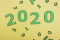 Green figures of date 2020, new year concept on yellow colored cardboard background, new year concept