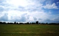 green filed under blue skies with white clouds Royalty Free Stock Photo