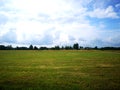 green filed under blue skies with white clouds