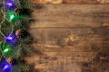 Green fir branches and Christmas lights on dark wooden table background. Creative layout frame made of Christmas fir branches, Royalty Free Stock Photo