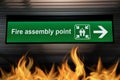 Green fire assembly point sign hanging from ceiling with fire Royalty Free Stock Photo