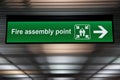 Green fire assembly point sign hanging from ceiling Royalty Free Stock Photo