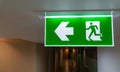 Green fire escape sign hang on the ceiling in the office Royalty Free Stock Photo