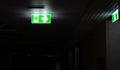 Green fire escape sign hang on the ceiling in the office at night Royalty Free Stock Photo