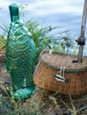 Green fish bottle,  Small wicker fishing basket with hole for small wooden fishing pole with hook on the end Royalty Free Stock Photo