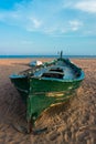 Green fishing boat on the beach and blue sky