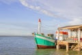 The green fishing boat is whitewashed against the pier with blue