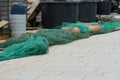 Green fishing net with red-brown floats stretched on the tiled pavement in port ready for loading on fishing boat. Royalty Free Stock Photo