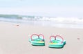 Green flip-flops embroidered on the sand and the hat at the sea with space of blue sky summer holiday and vacation concept Royalty Free Stock Photo